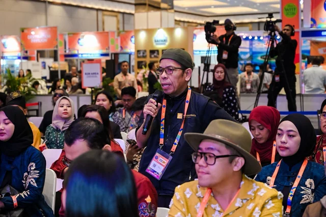 Pak Indra holding a microphone while standing among participants in the WISH 2026 forum.