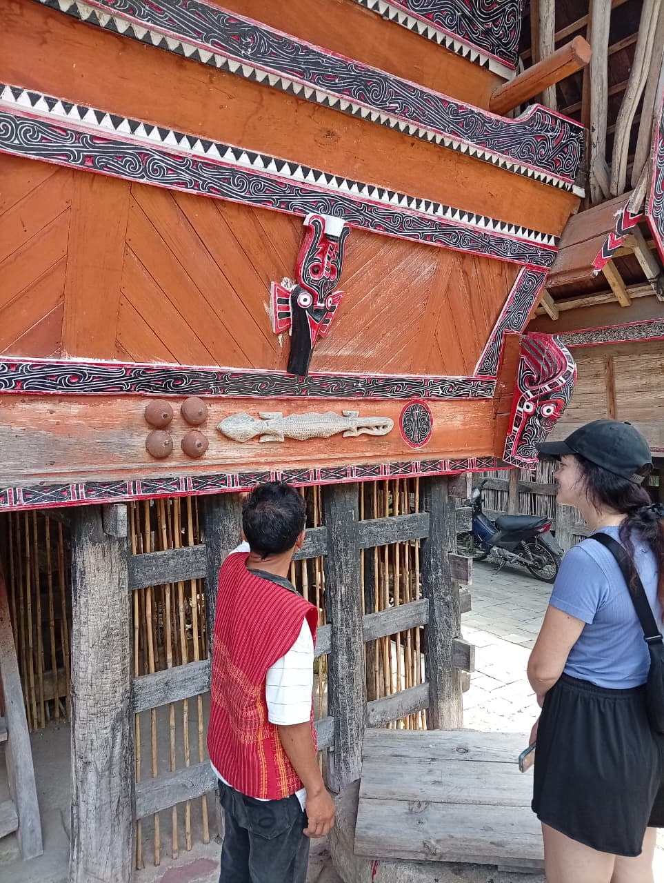 A local guide explaining Batak house details to an adult guest