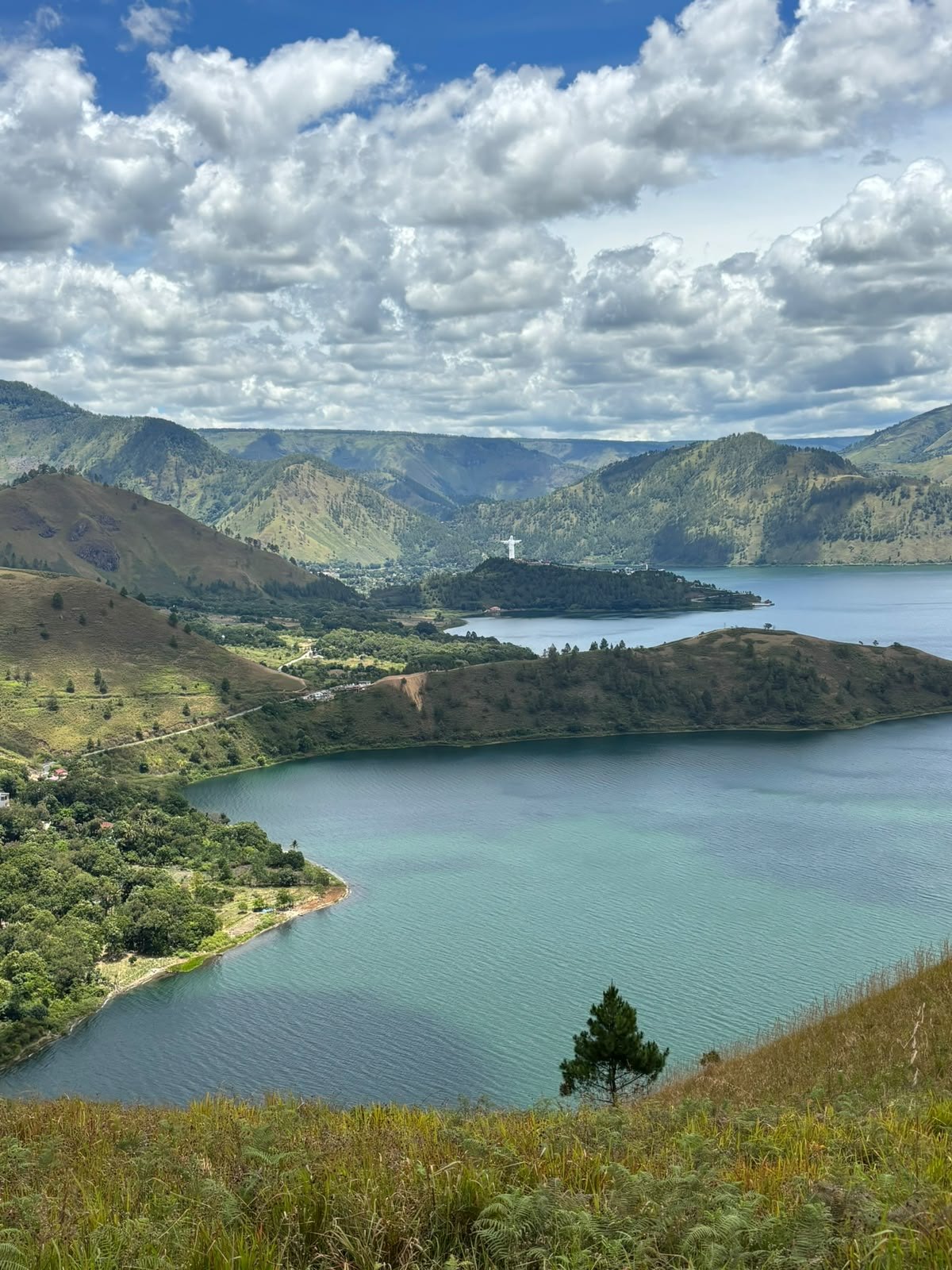 Lake Toba bays and hills. Curving shores, green hills, and clouds over Lake Toba.